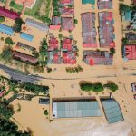 Vista aérea de casas e árvores cercadas por água após uma inundação