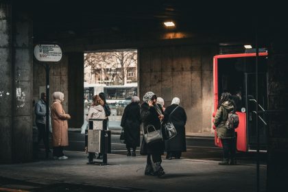 Passageiros aguardam um ônibus em um ponto de transporte público urbano.