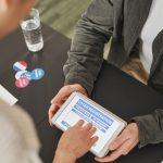 Pessoa realiza cadastro eleitoral em um tablet em uma estação de votação moderna.