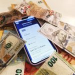 Smartphone exibindo um conversor de moedas, cercado por cédulas de dólar e euro.