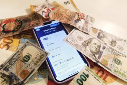 Smartphone exibindo um conversor de moedas, cercado por cédulas de dólar e euro.
