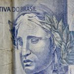Close-up de uma cédula brasileira de dois reais, destacando seus elementos gráficos.