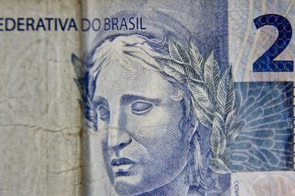 Close-up de uma cédula brasileira de dois reais, destacando seus elementos gráficos.